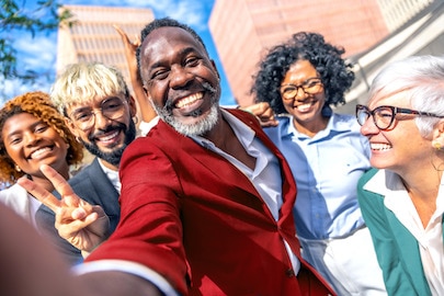 不同年齡、種族和性別的人在建築物外笑容滿面