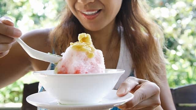 用湯匙吃碗中刨冰的人