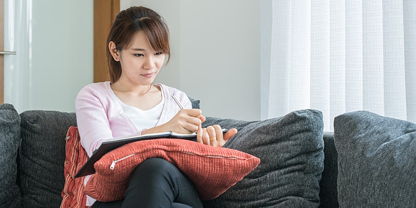 客廳沙發上寫筆記，膝上抱枕