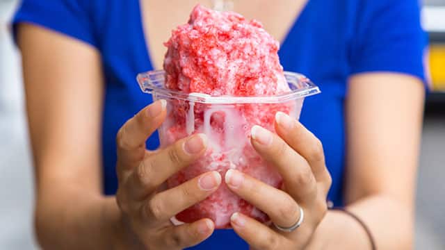 雙手捧著紅色刨冰杯的人