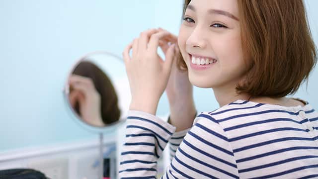 穿條紋上衣的人在圓鏡前整理臉部