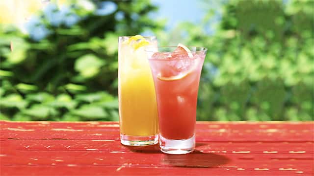 戶外紅桌上兩杯冰果汁，一橙一粉