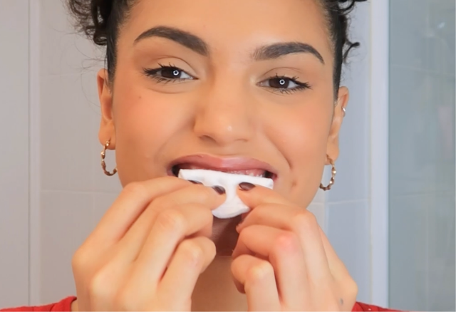 女士用紙巾輕輕印乾牙齒表面。