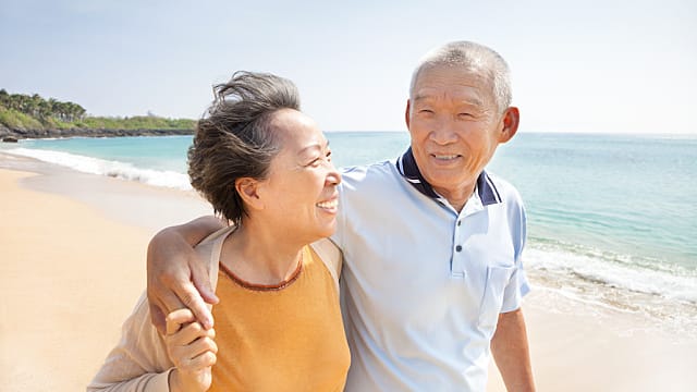 happy asian seniors walking on the beach